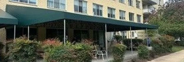Apartment building with green awnings and a landscaped walkway in front