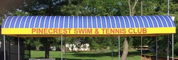 Pinecrest Swim & Tennis Club sign on a yellow awning with blue striped top