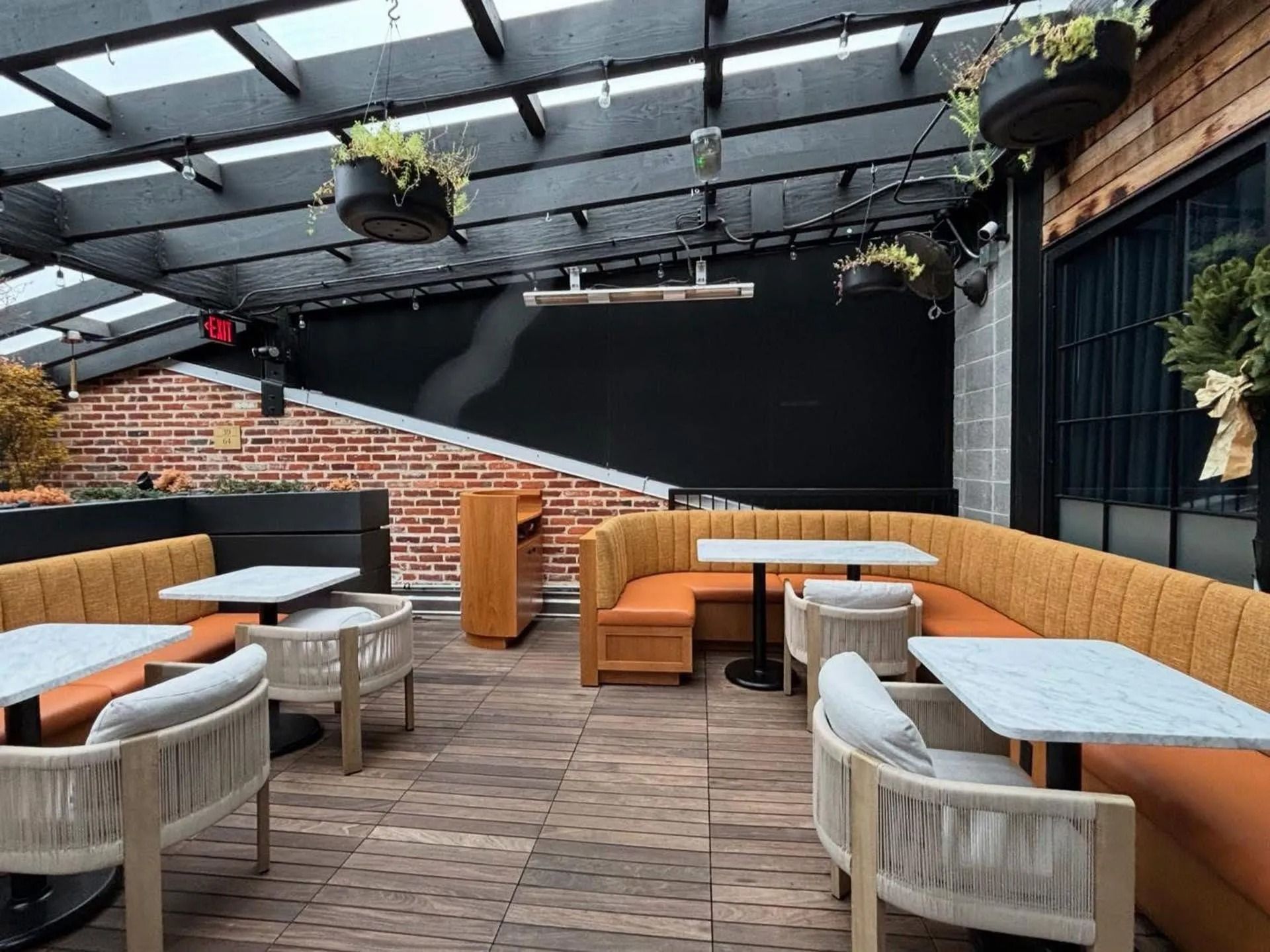 Outdoor patio with wicker seating, tables, and hanging plants under a covered pergola.