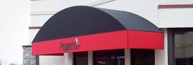 Red storefront awning with black arched top above a shop entrance