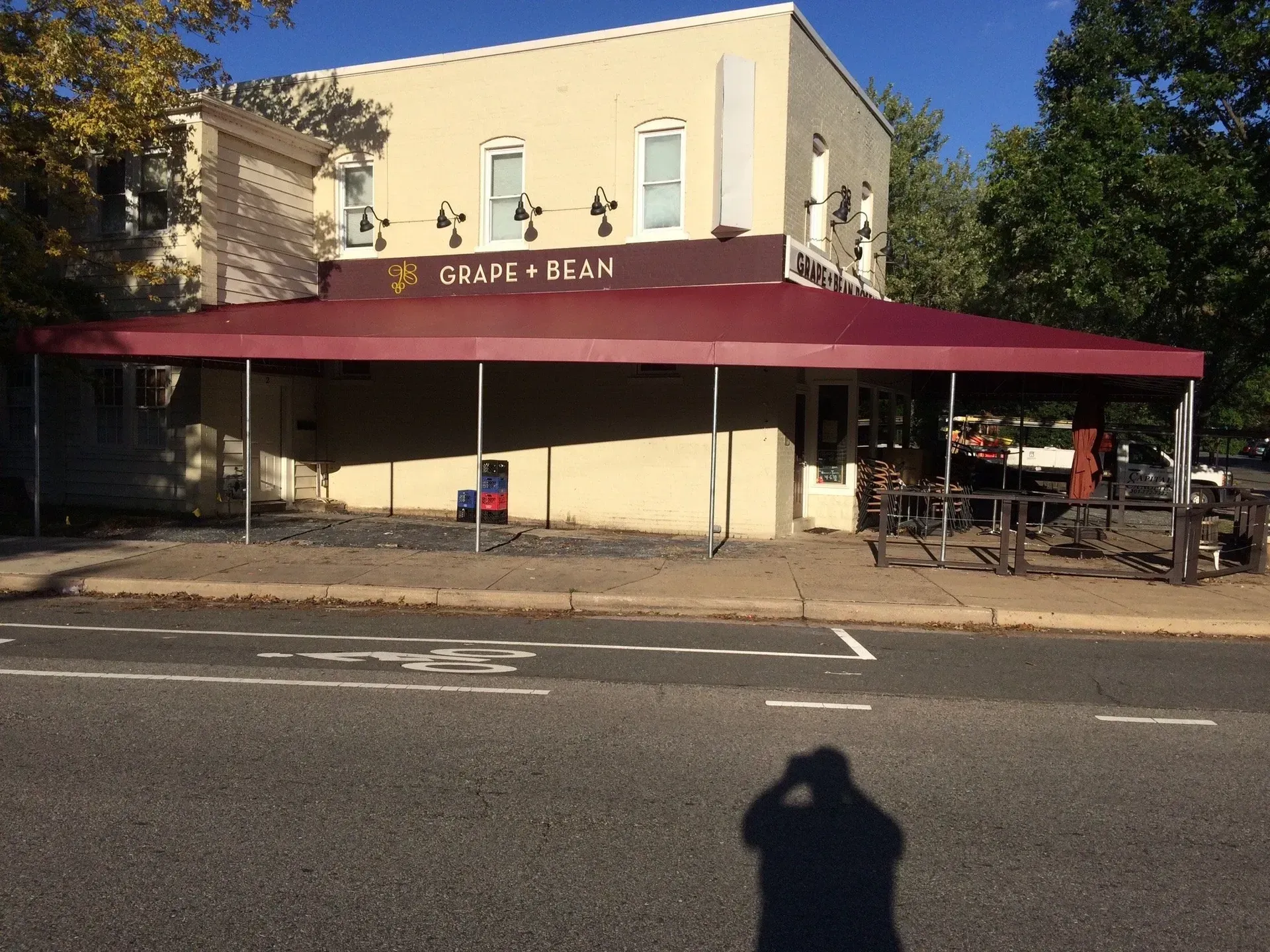 Cafe storefront with maroon awning and outdoor seating on a sunny street corner