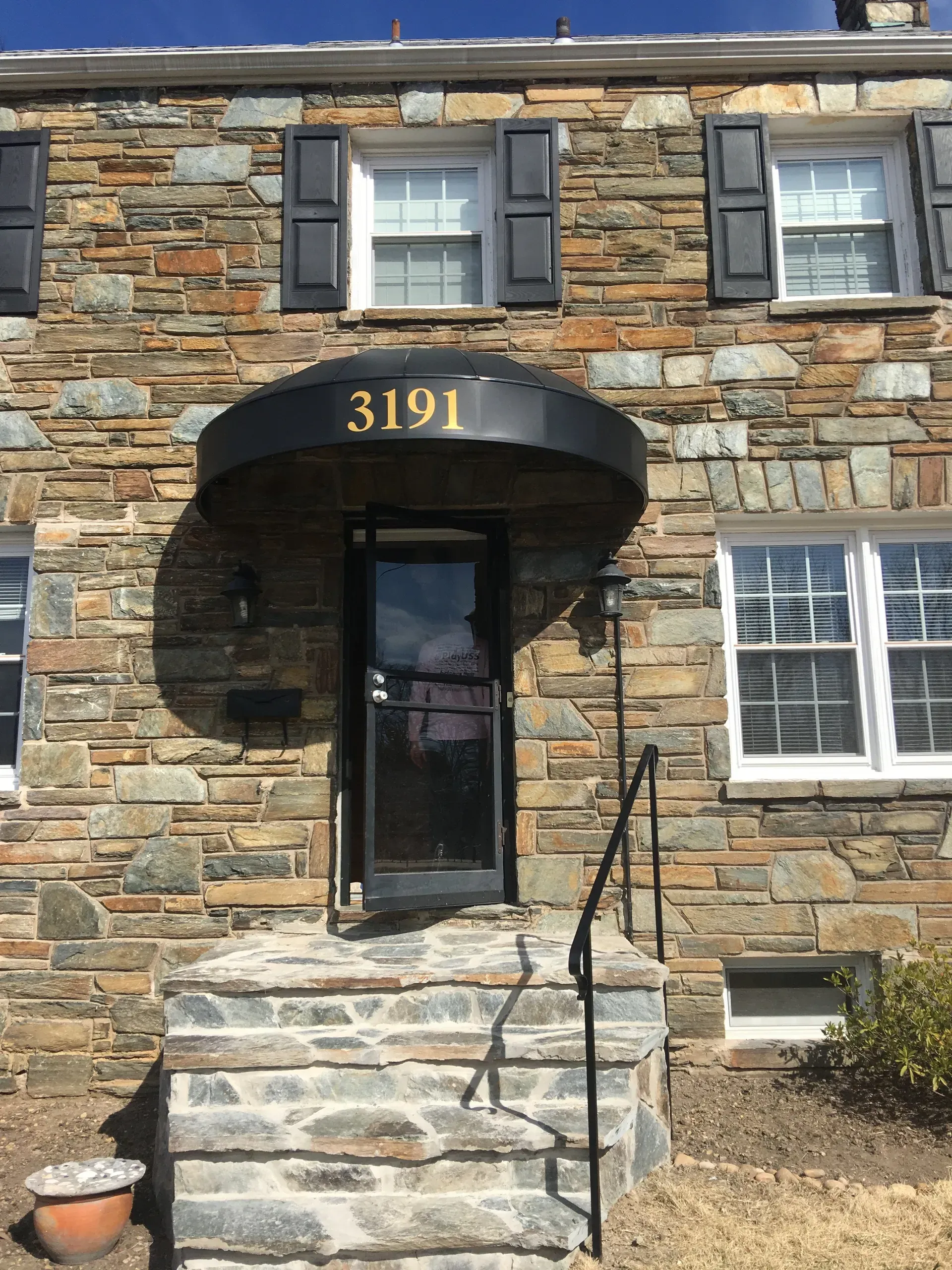 Stone house entrance with black door, arched awning, and steps leading to the front door marked 3191.