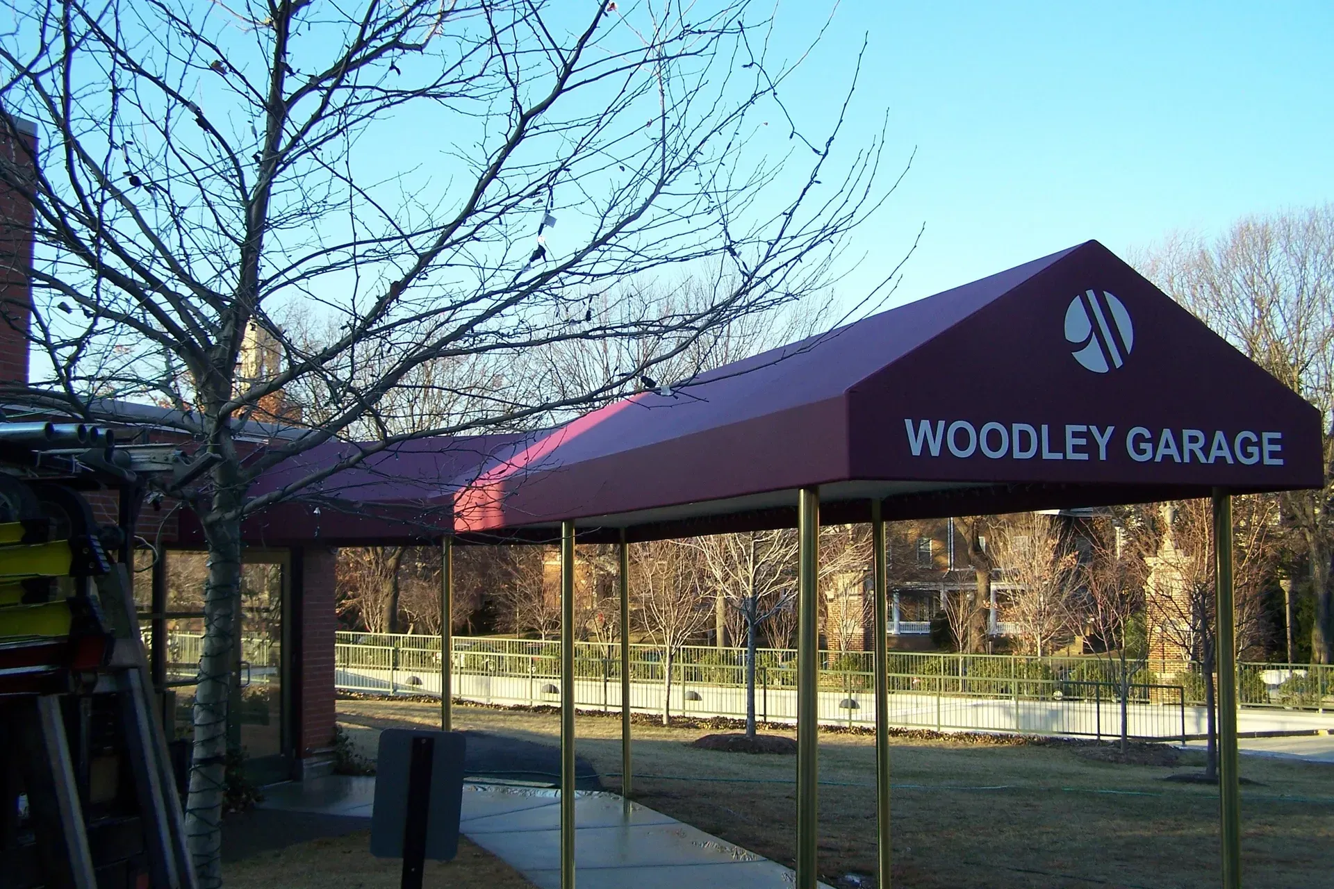 Woodlev garage entrance with maroon canopy and bare trees in a park-like setting