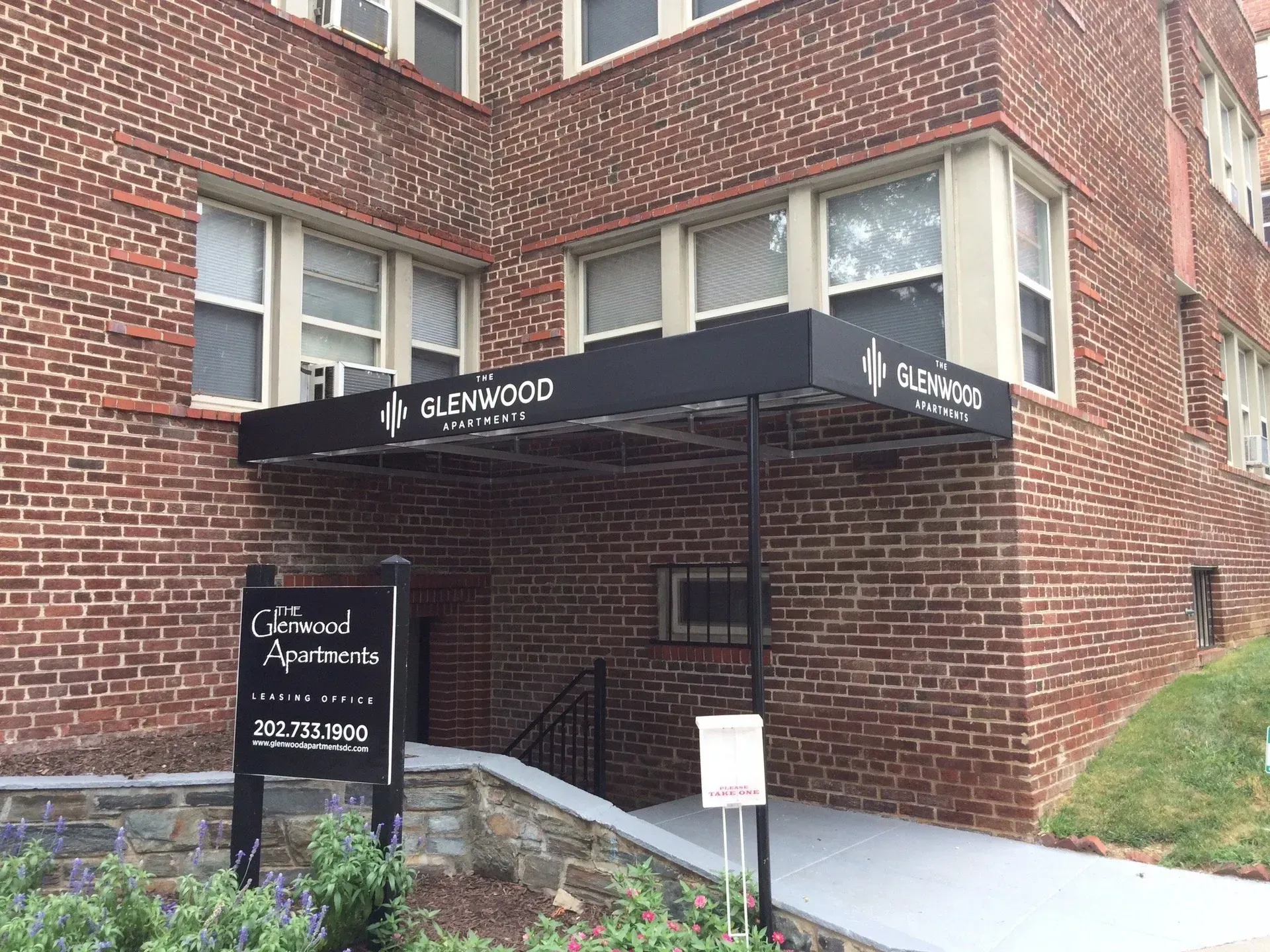 Brick building entrance with black awning and stairs leading to a doorway