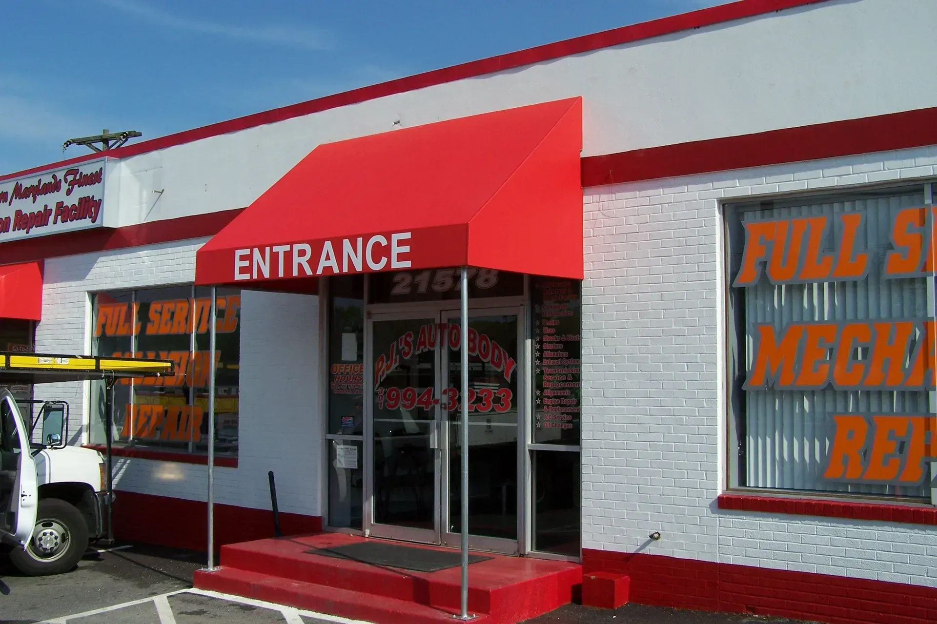 Auto repair shop entrance with red awning and white brick facade