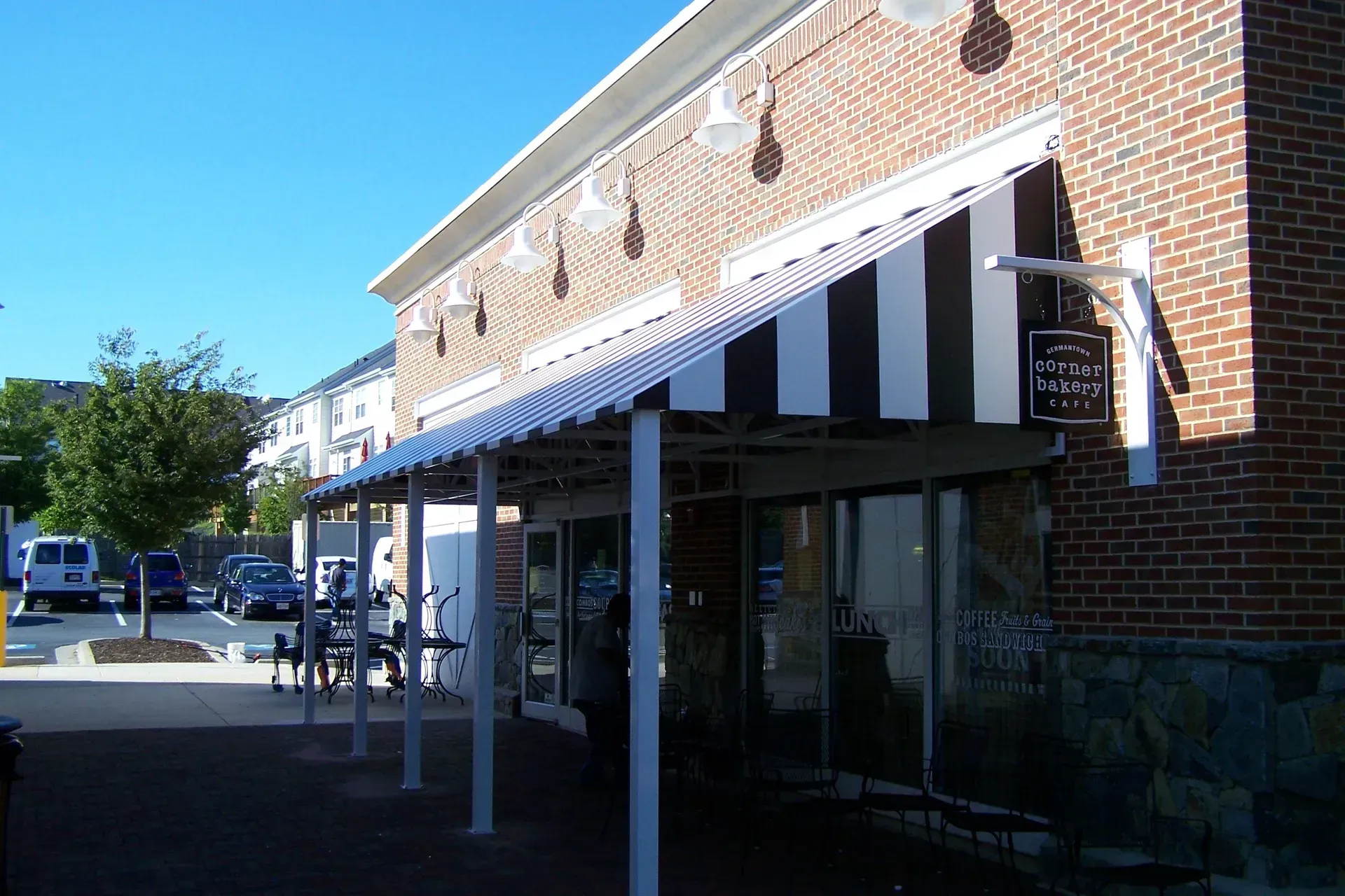 Striped awning over a brick storefront on a sunny street corner