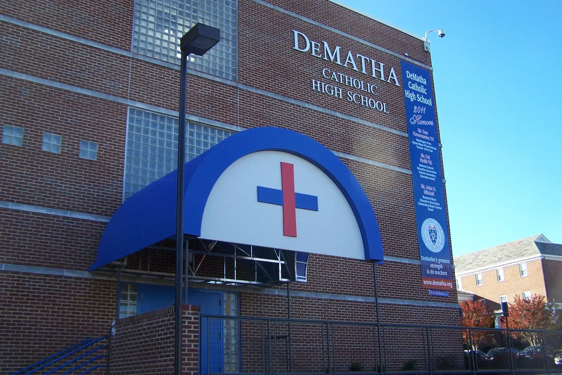 Brick building with a blue awning and red cross above the entrance, likely a medical center.