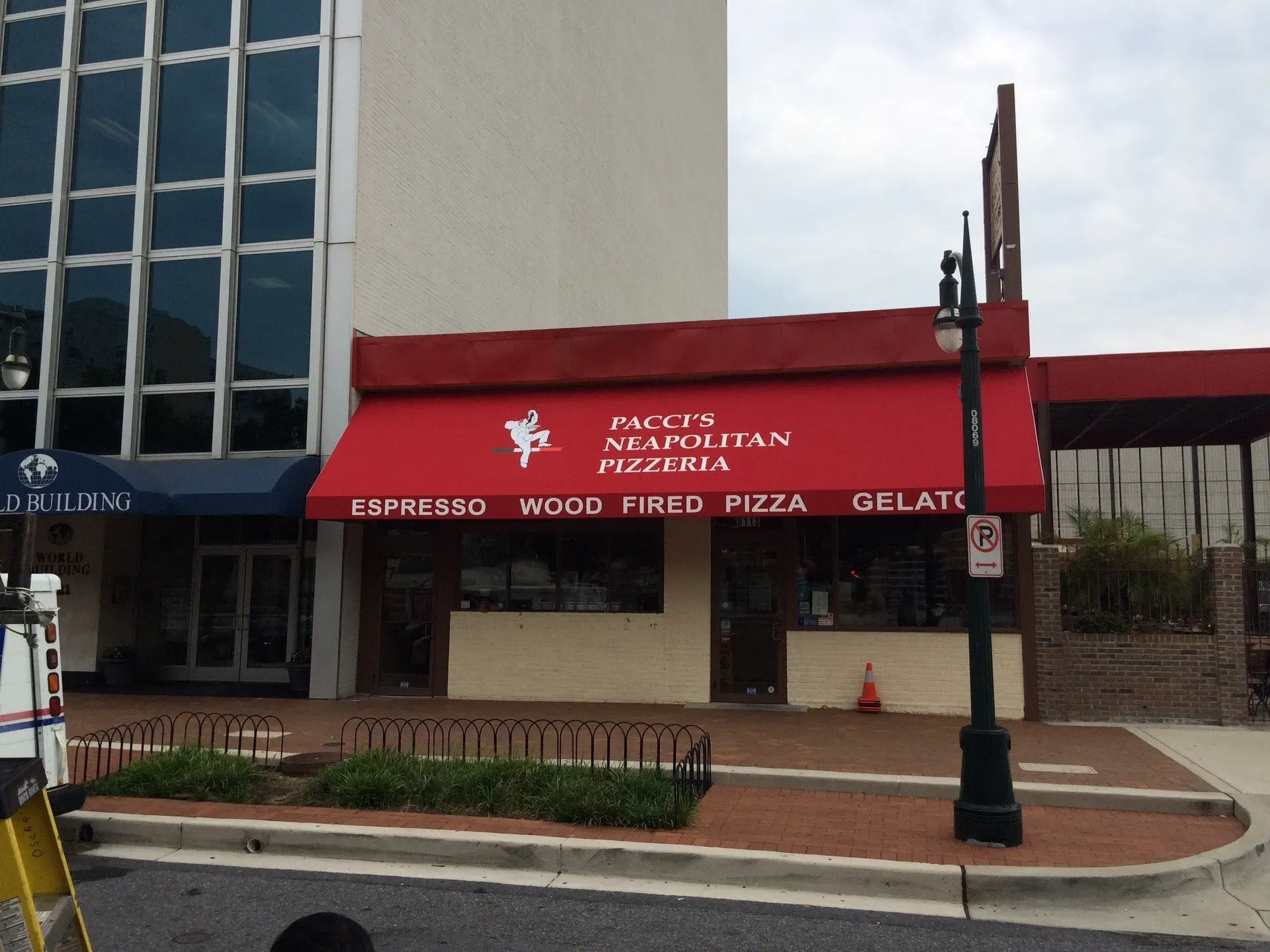 Red awning storefront for an Italian cafe next to a glass office building