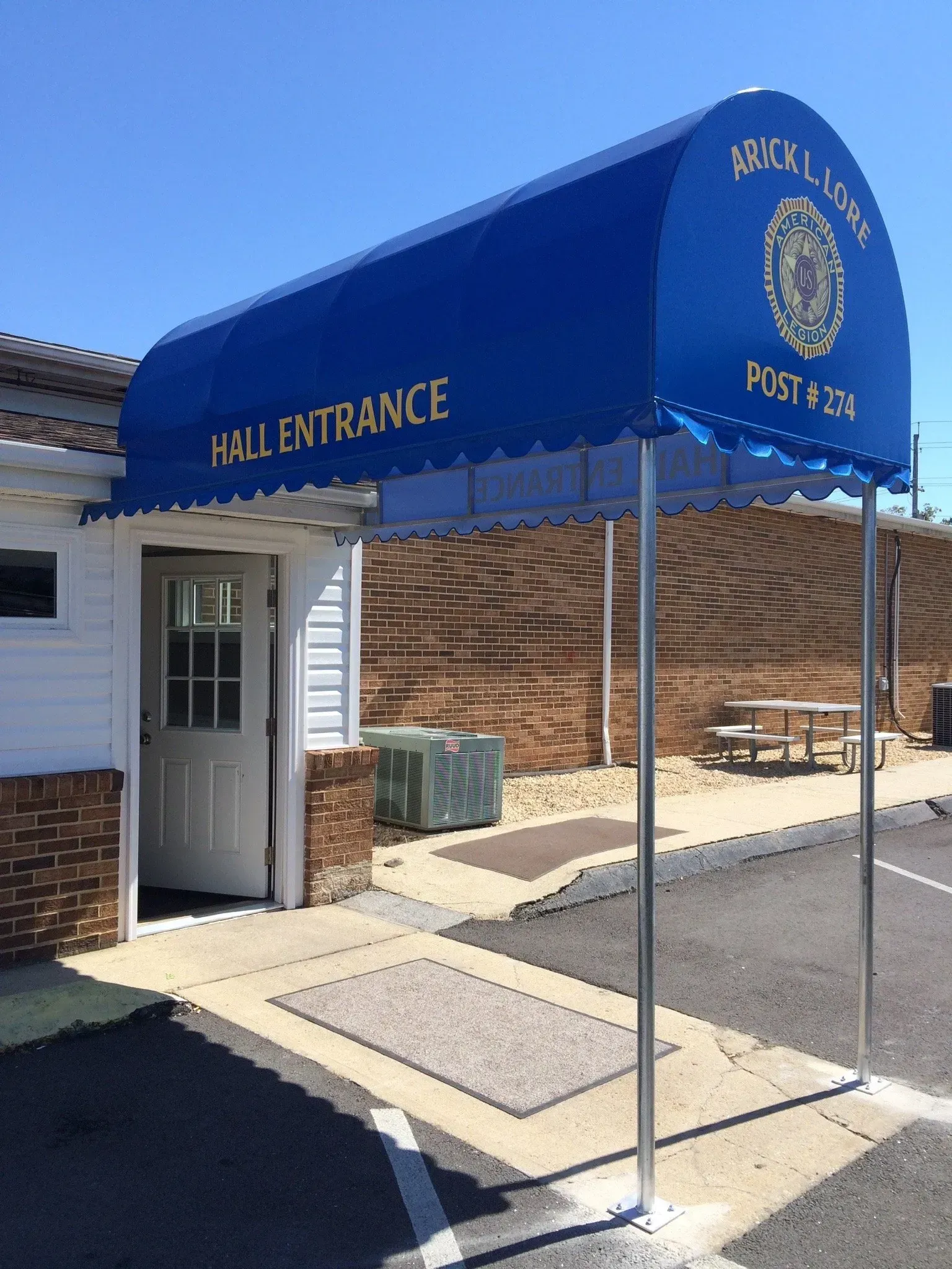 Blue awning marked “Hall Entrance” over a doorway at a brick building entrance