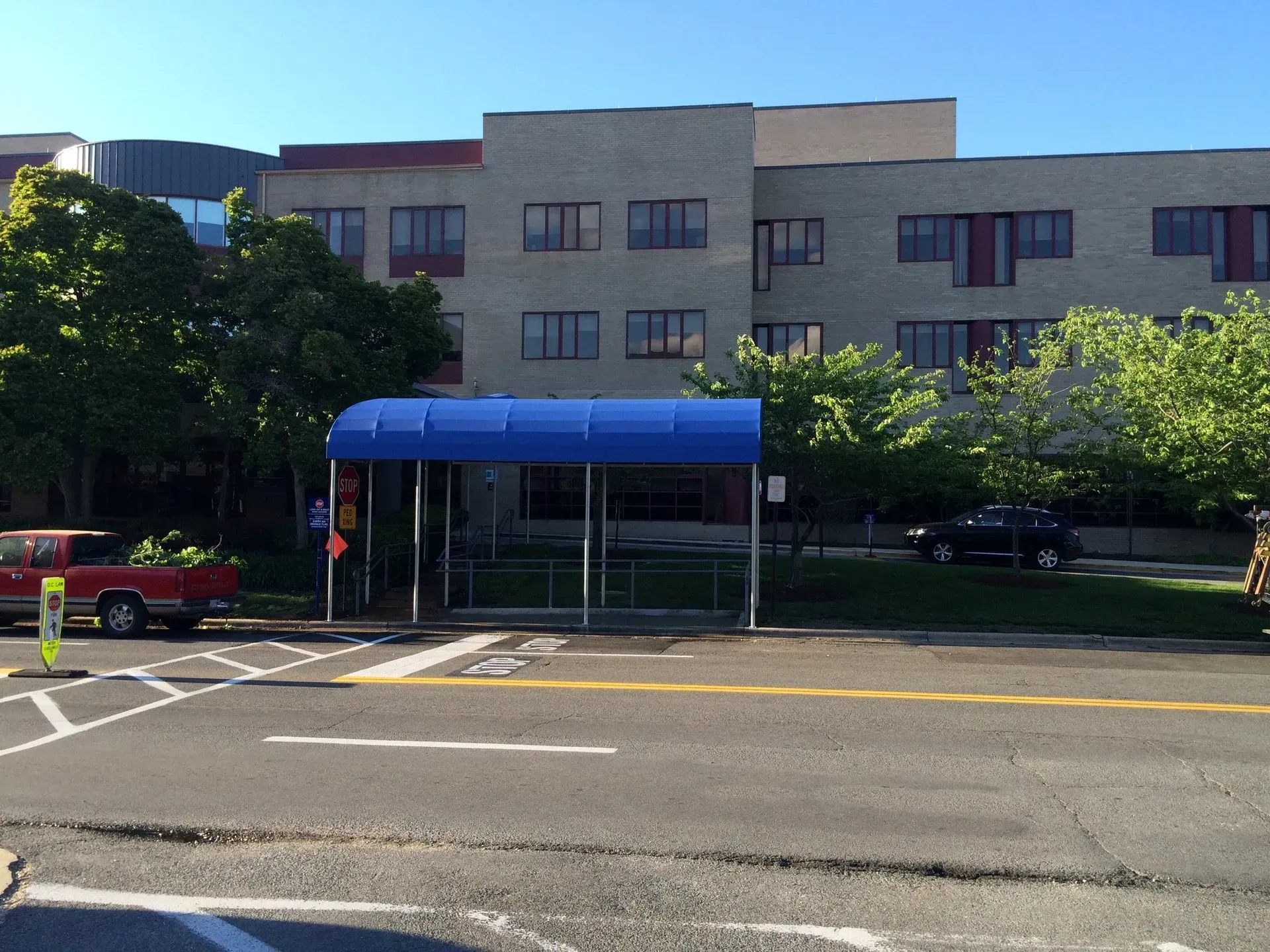 Building entrance with blue awning, trees, and empty street in front