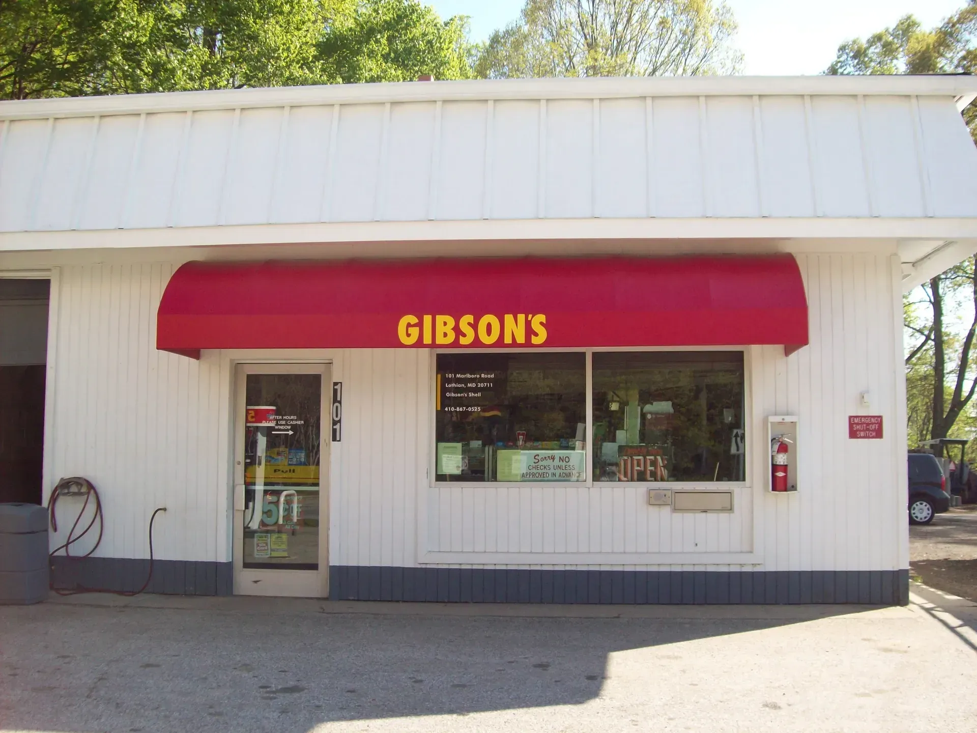 Small white storefront with red awning labeled “GIBSONS” and a glass entrance door