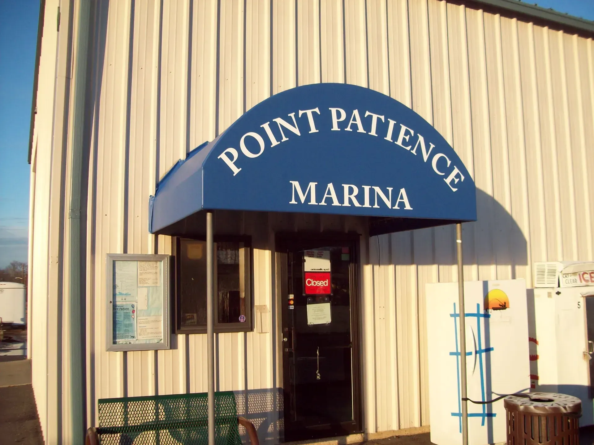 Blue awning reading “Point Patience Marina” over a small beige building entrance