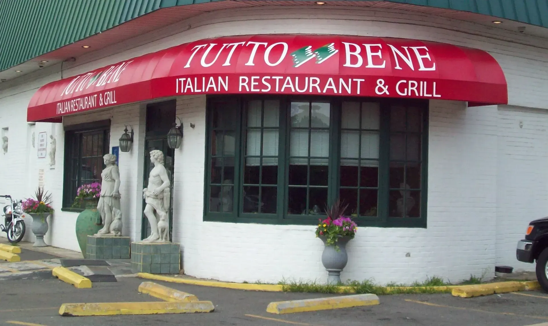 Tutto Bene Italian Restaurant & Grill storefront with red awning and statues by the entrance