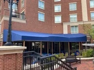 Brick building with blue awning over a patio entrance and black railings