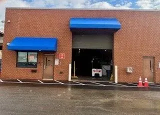 Brick building with blue awnings, open garage bay, and cones on a wet pavement