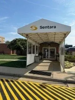 Sentara hospital entrance with white canopy, walkway, and yellow-black striped curb