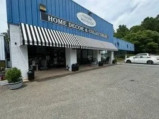 Storefront with blue facade and black-and-white striped awnings in a parking lot