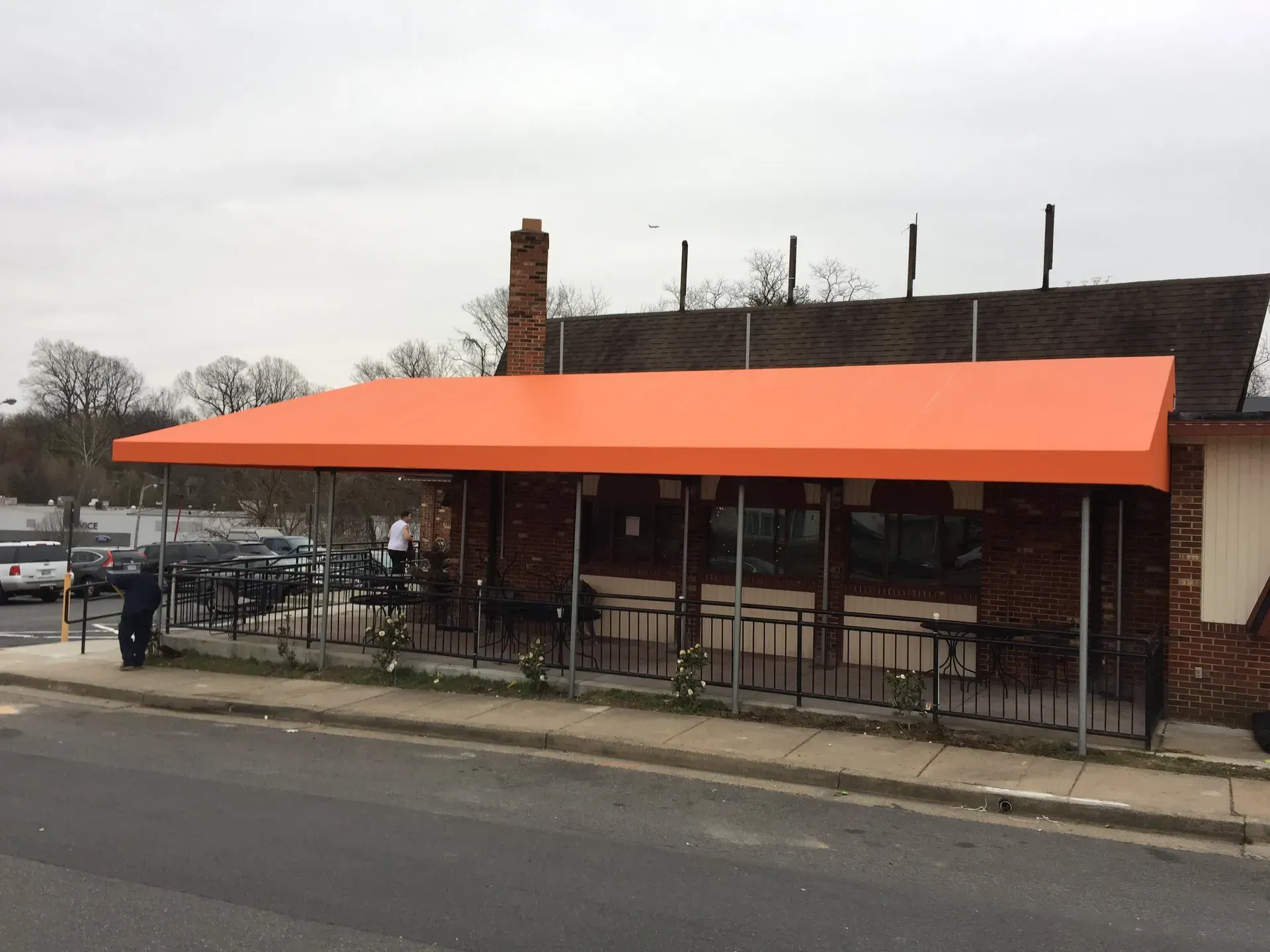 Street-side café with bright orange awning and outdoor seating by the road