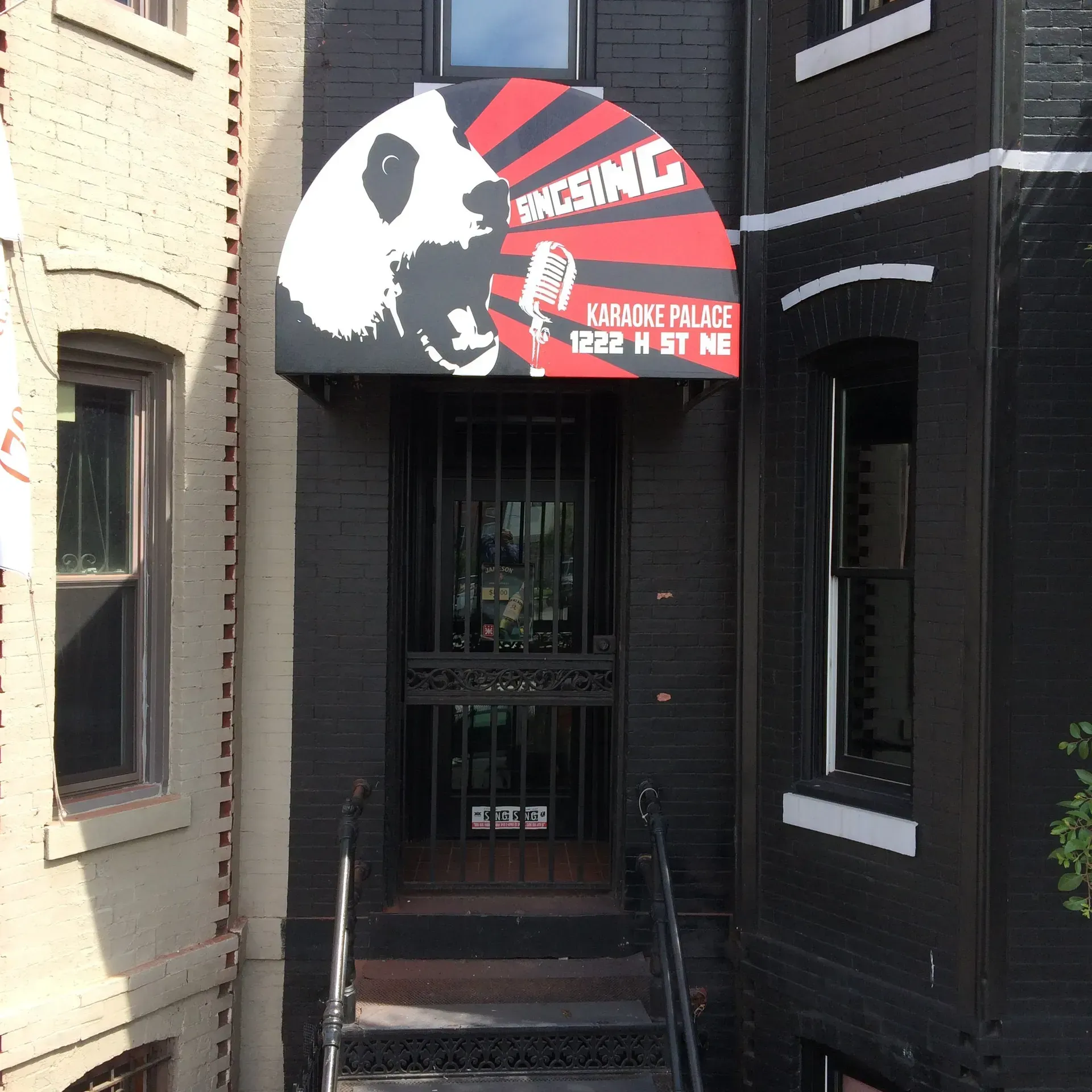 Black storefront entrance with red awning reading “Rising” and “Community Center” above steps