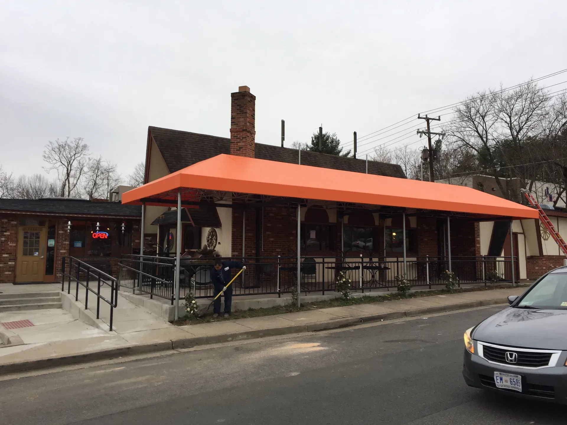 Small brick restaurant with orange awning and outdoor seating on a street corner