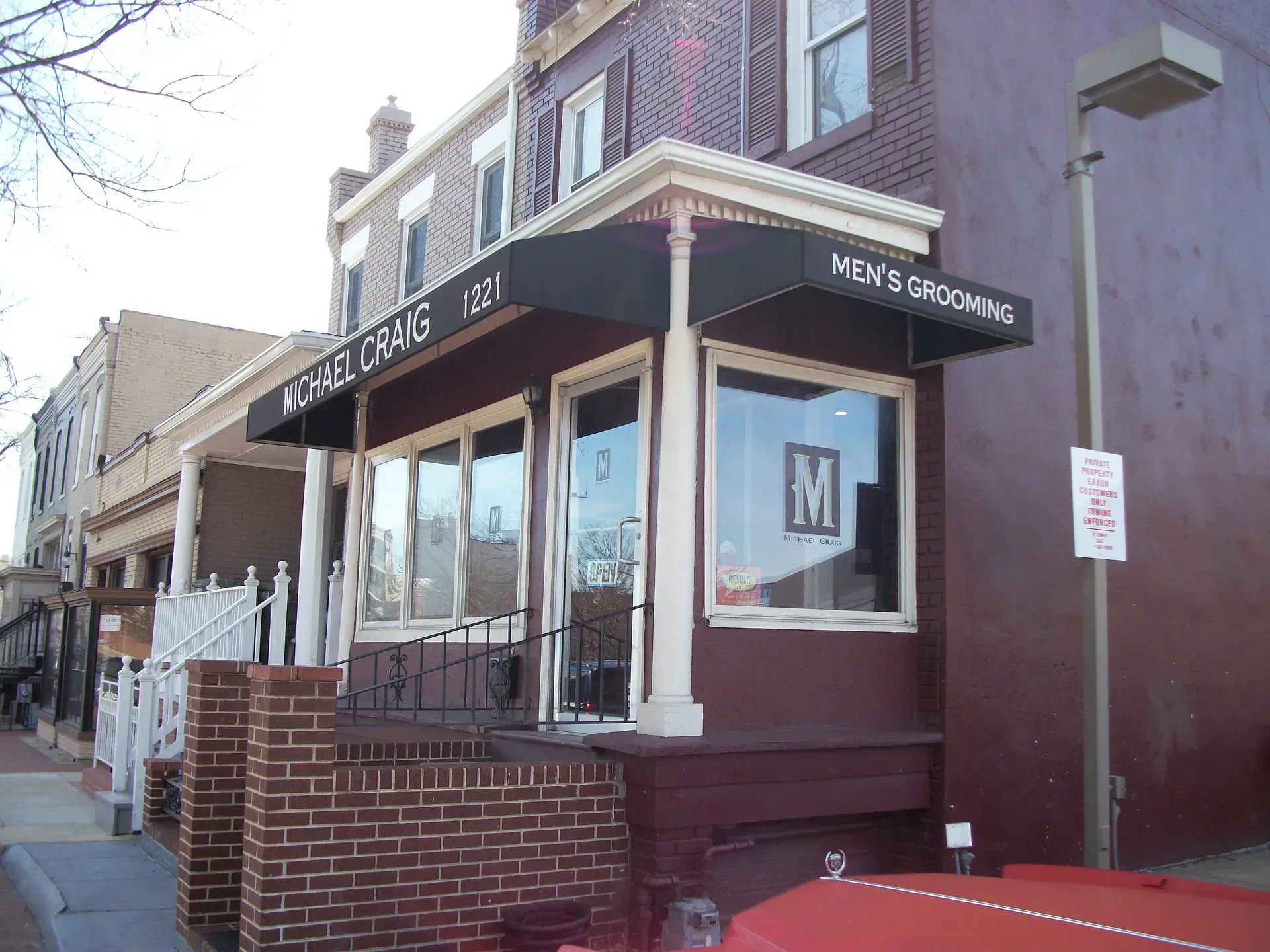 Corner storefront with brick facade, black awning, and large windows on a city street.