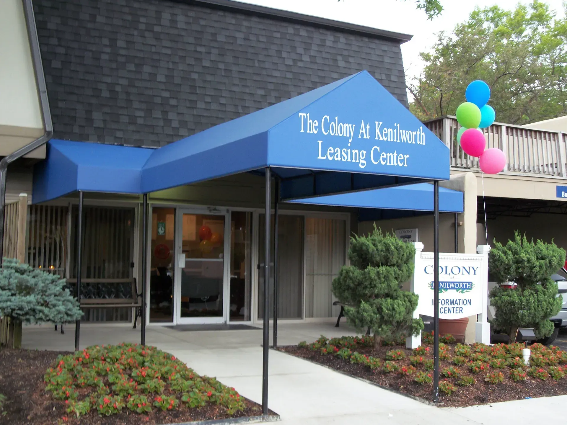 The City of Fairview Leasing Center entrance with blue awning, glass doors, and balloons outside