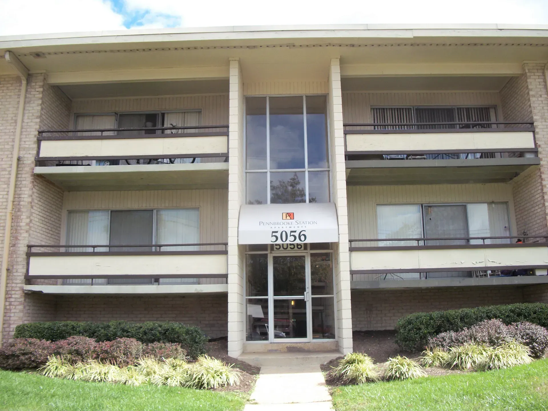 Front view of a beige apartment building with balconies and the address 5056 above the entrance