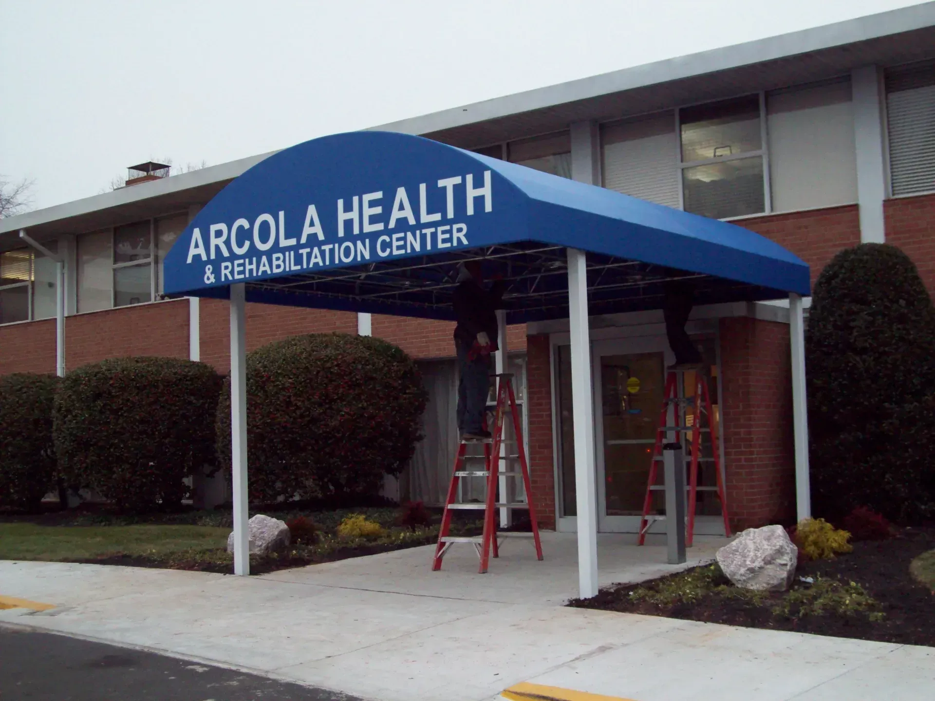Arcola Health & Rehabilitation Center entrance with blue awning and red ladder under it