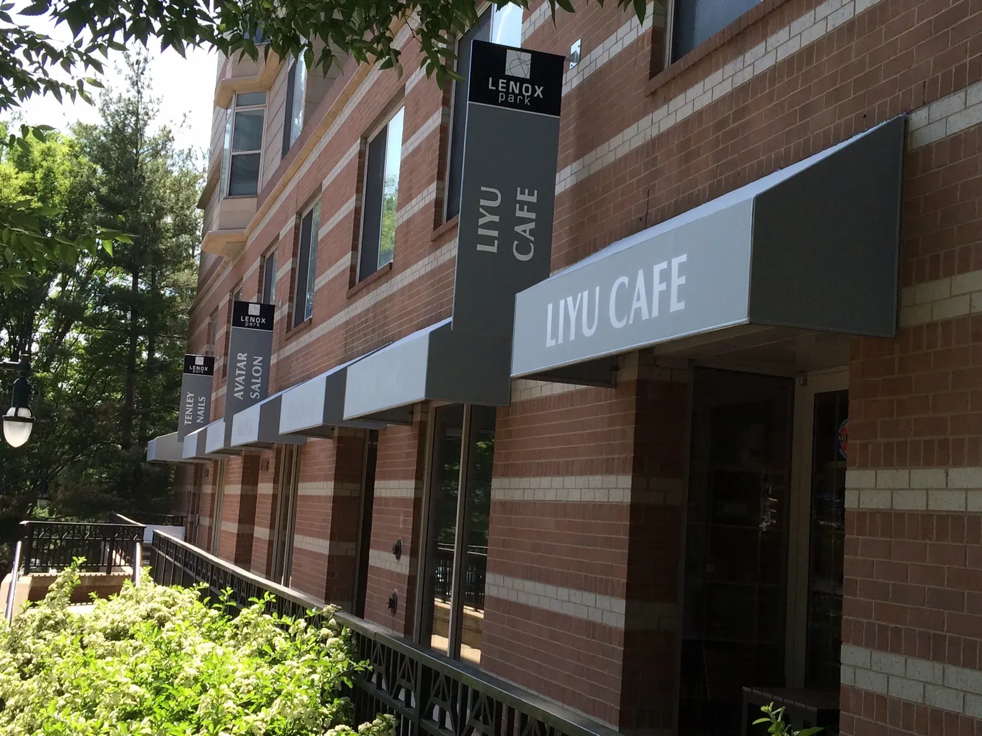 Brick storefront with awnings for Ivy Cafe along a tree-lined sidewalk