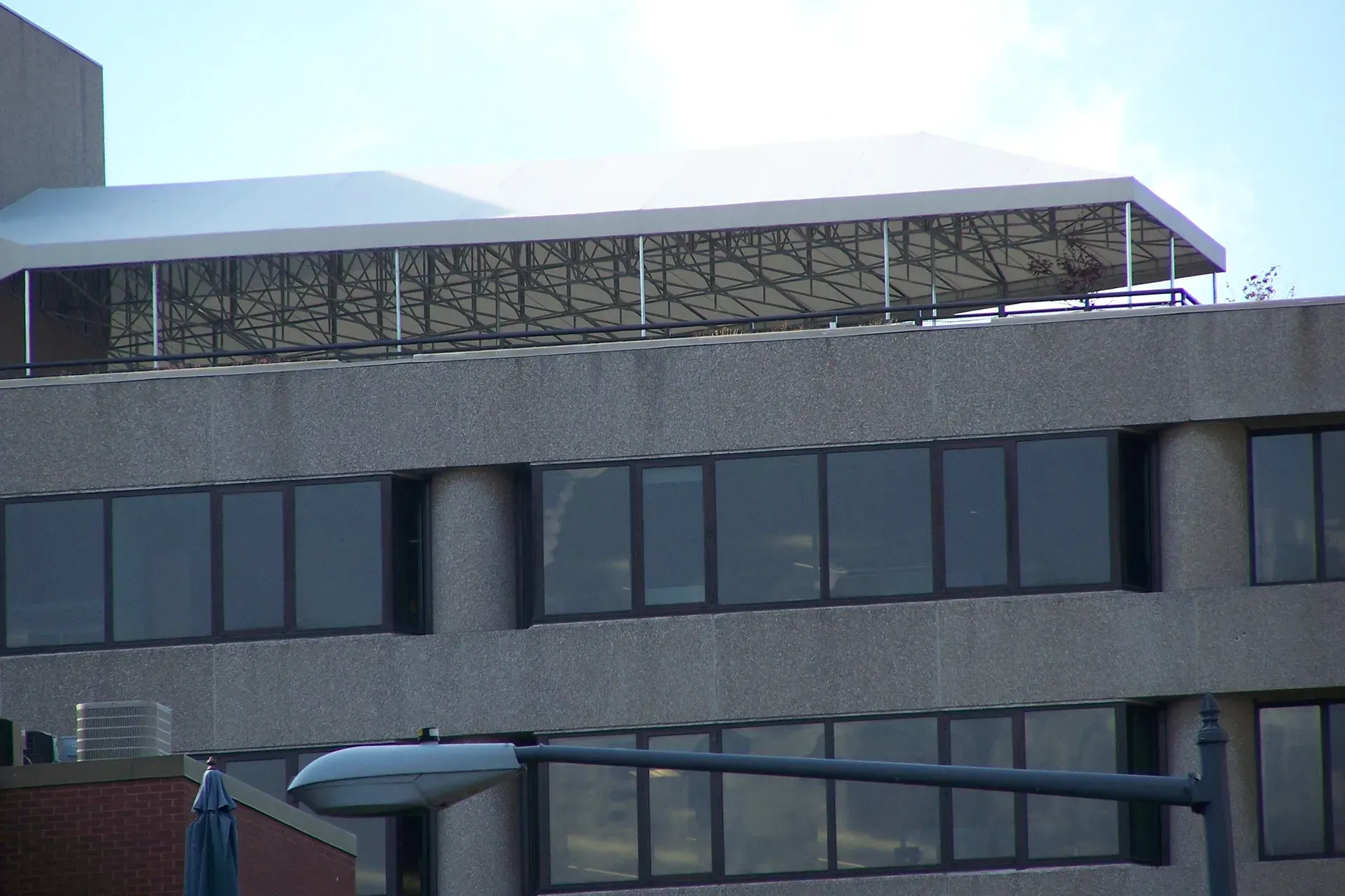 Modern concrete building with dark windows and a white roof canopy