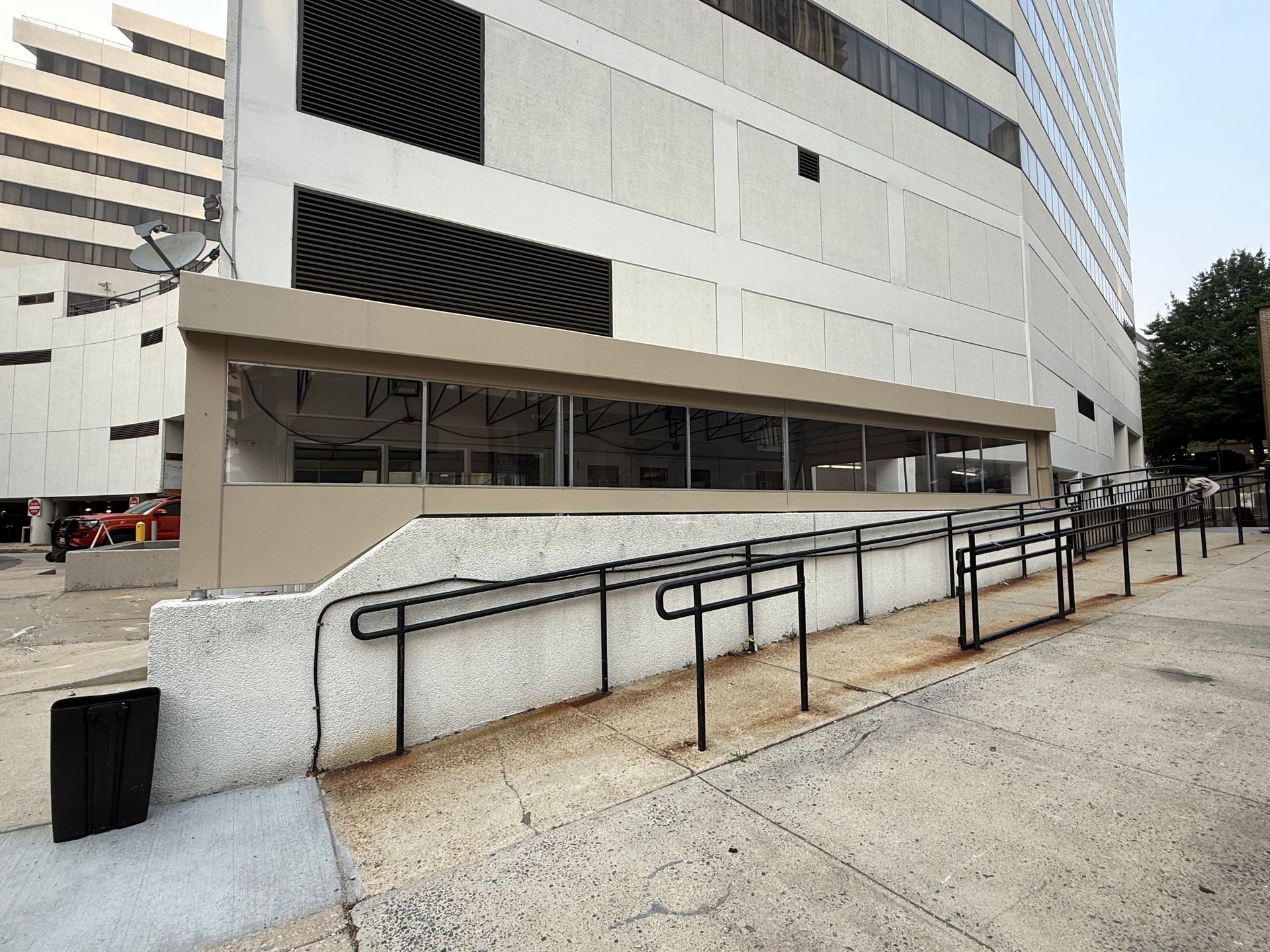 Exterior of a modern office building with a sloped ramp and black handrails.