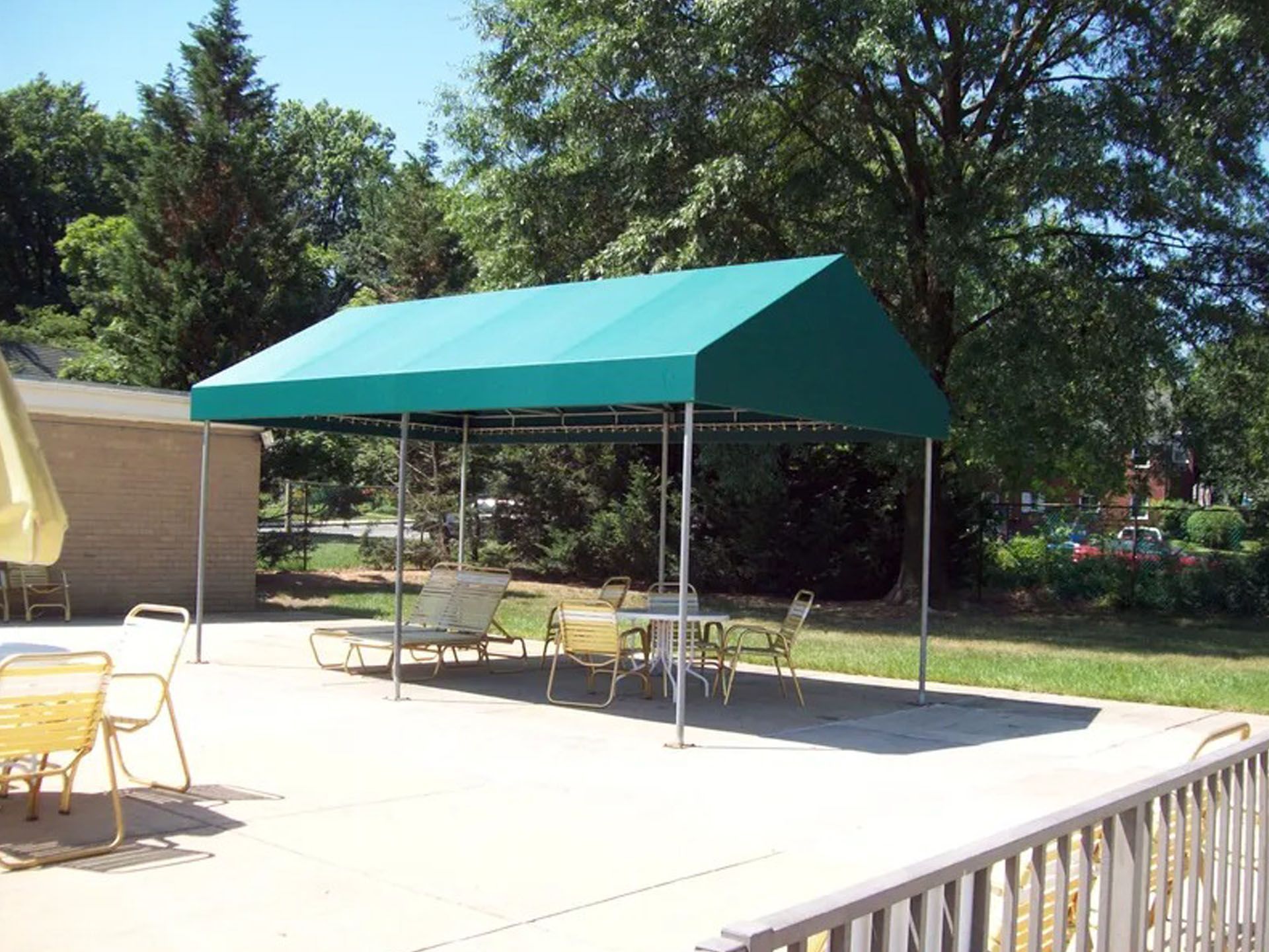 Green canopy tent with tables and chairs on a sunny outdoor patio