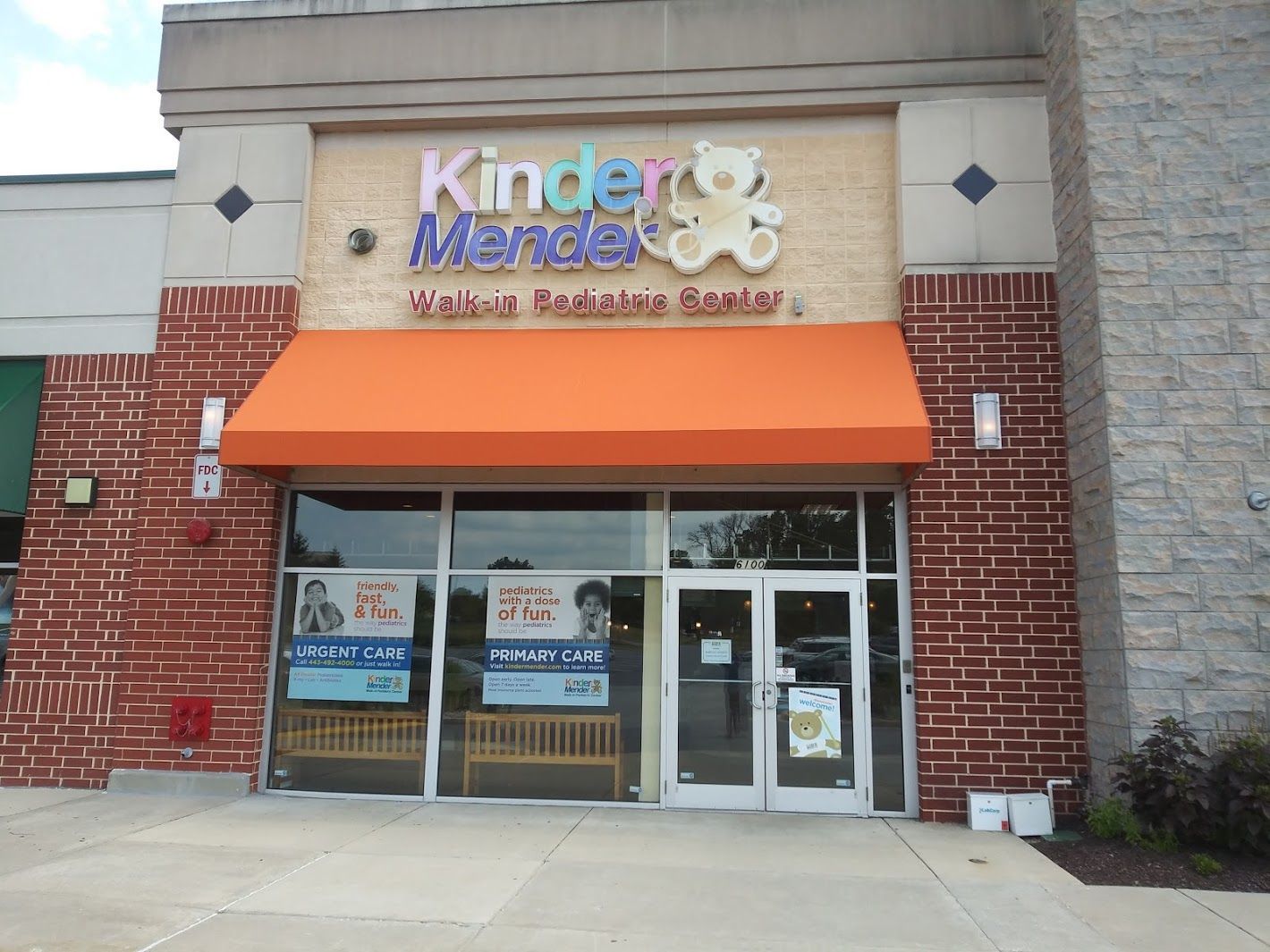 Storefront of Kinder Menders Learning and Behavioral Services with orange awning and glass entrance.