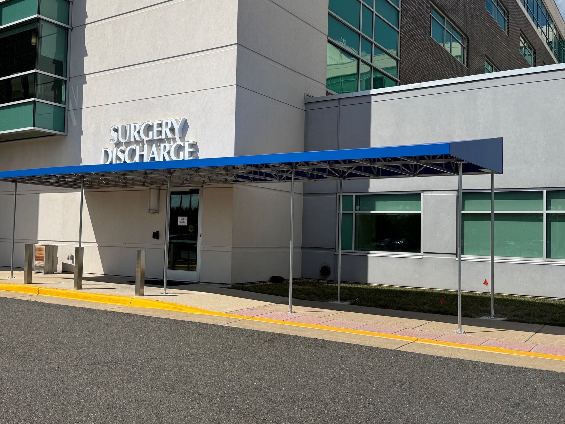 Hospital discharge entrance with blue awning and glass windows.