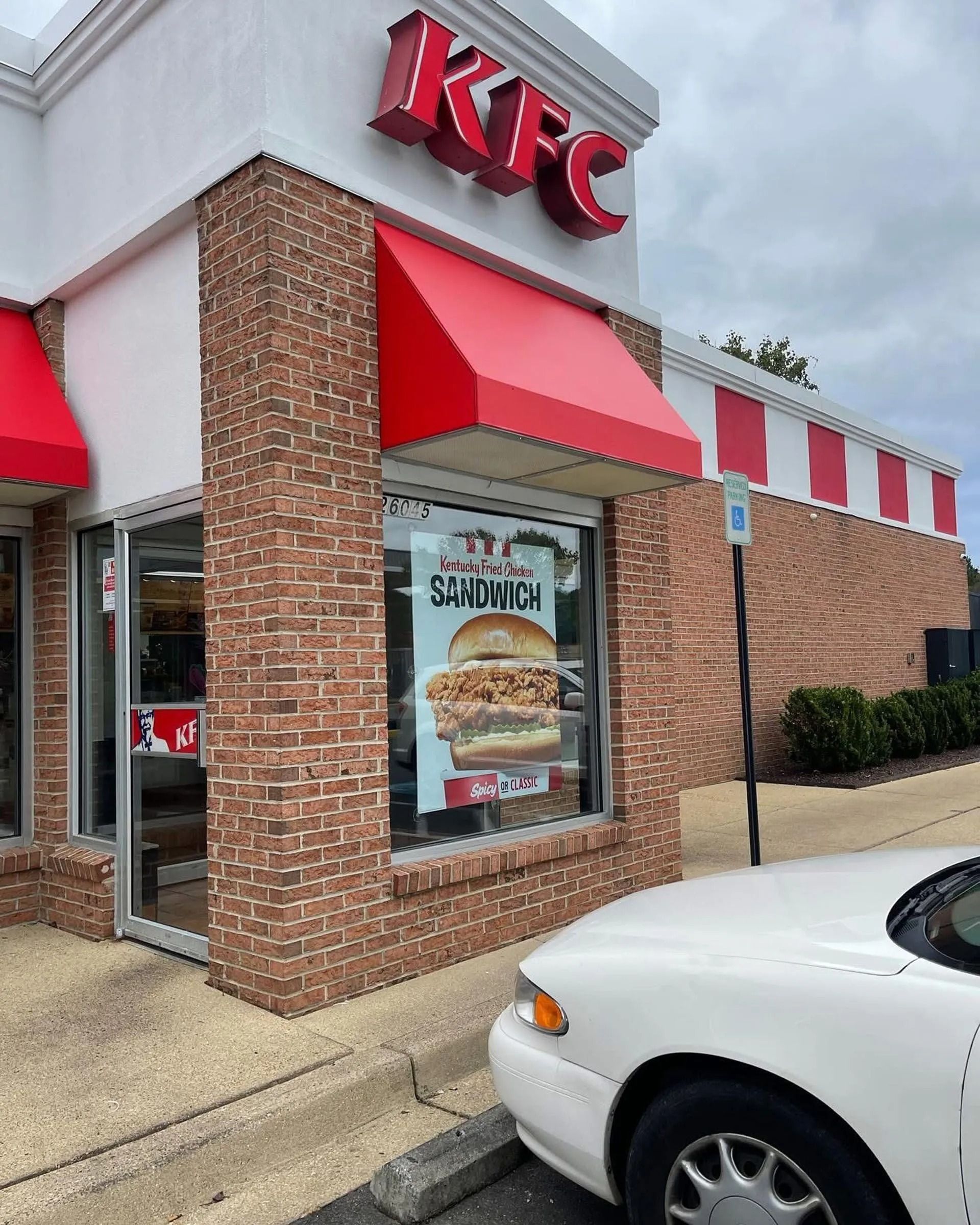 KFC restaurant exterior with red awnings and a white car parked outside
