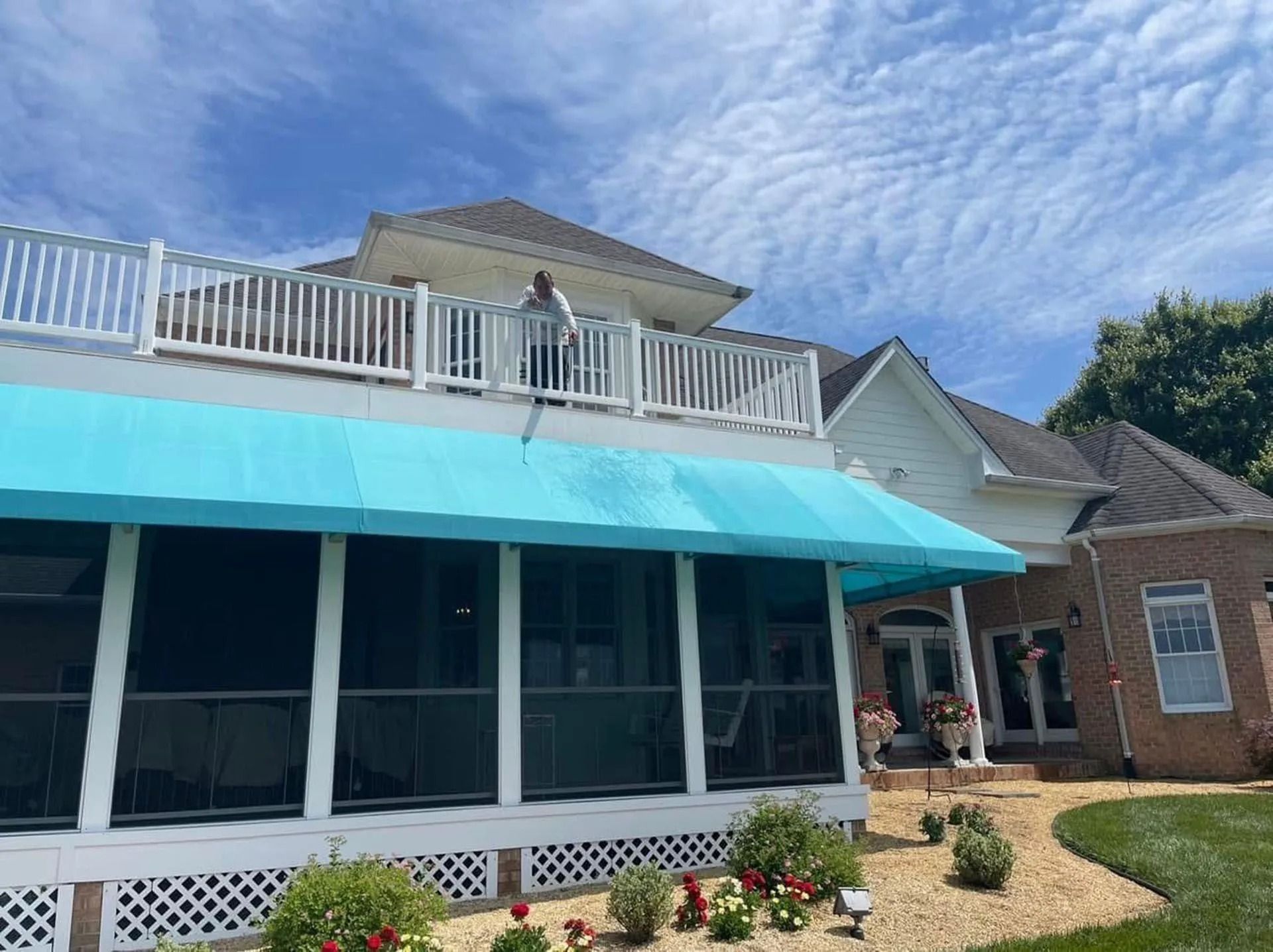 A turquoise-awning storefront with a white balcony and a person standing on the upper deck.