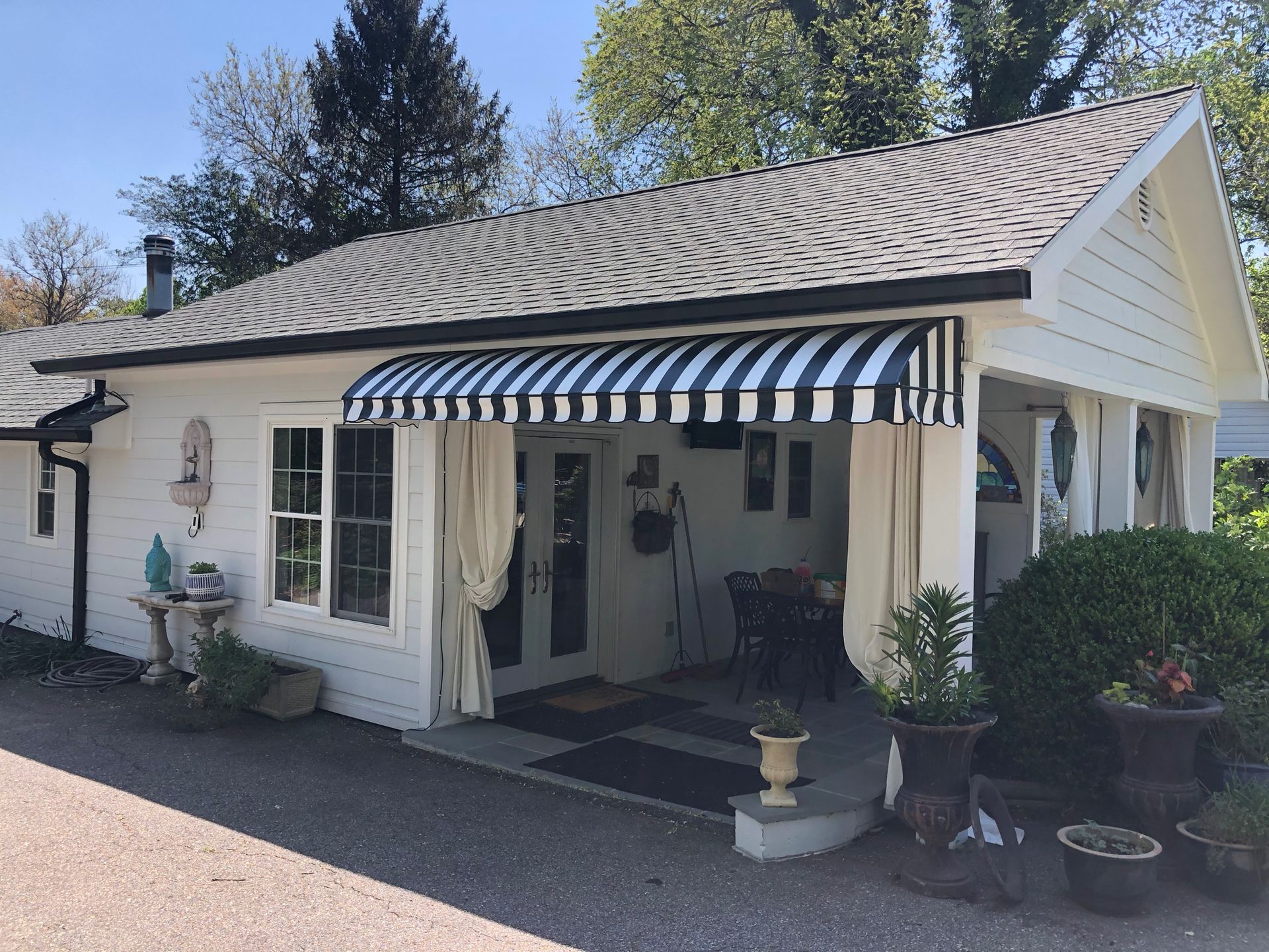 White storefront with blue-and-white striped awning and potted plants by the entrance.