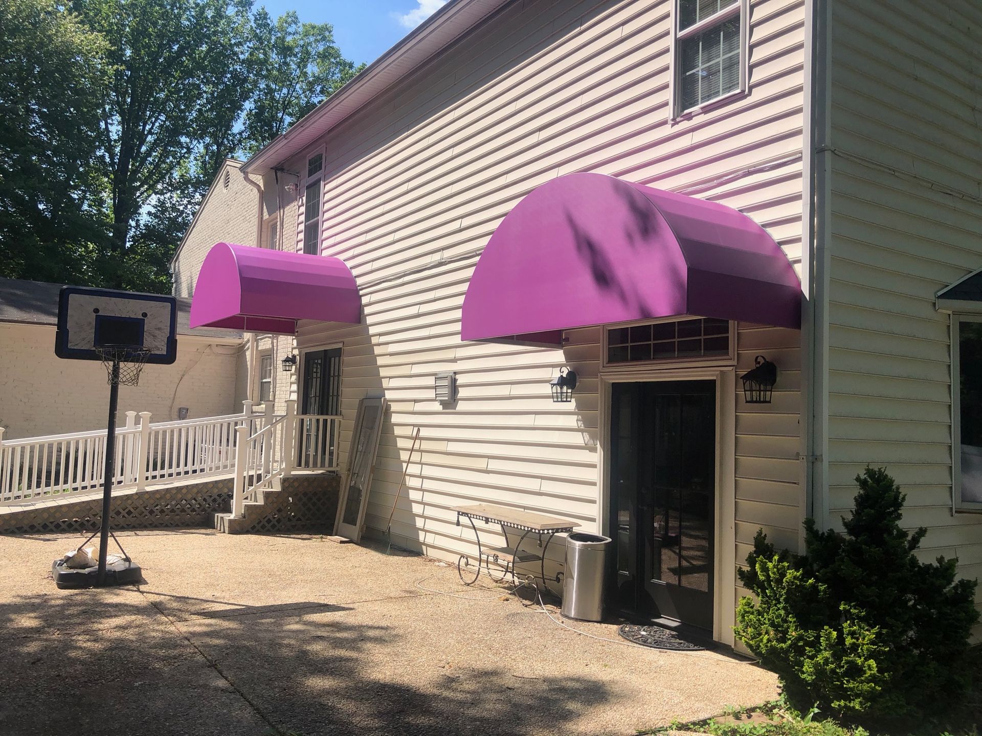 House exterior with two purple awnings over doors and a small porch area.