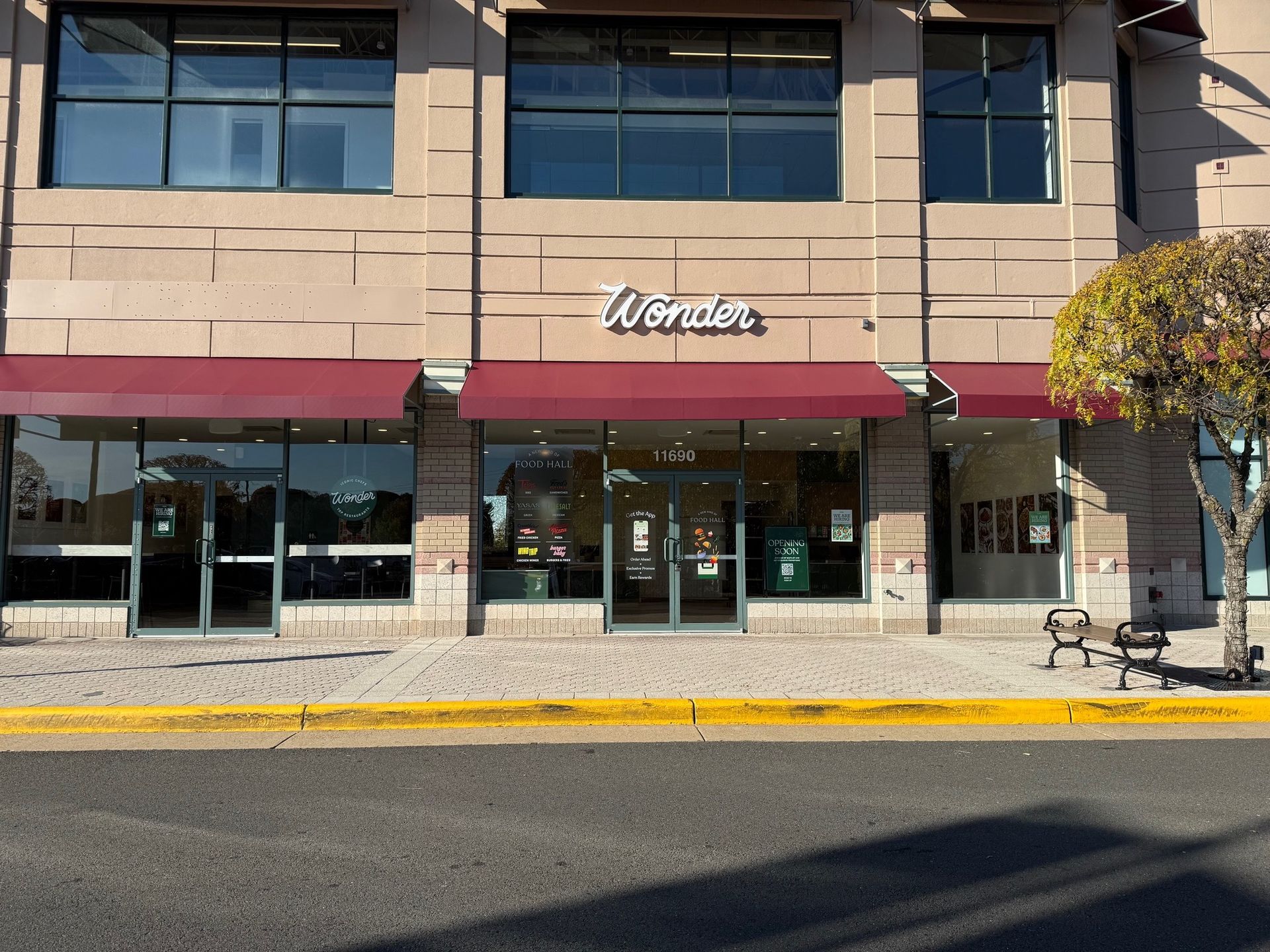 Storefront with maroon awnings and large windows along a city sidewalk.