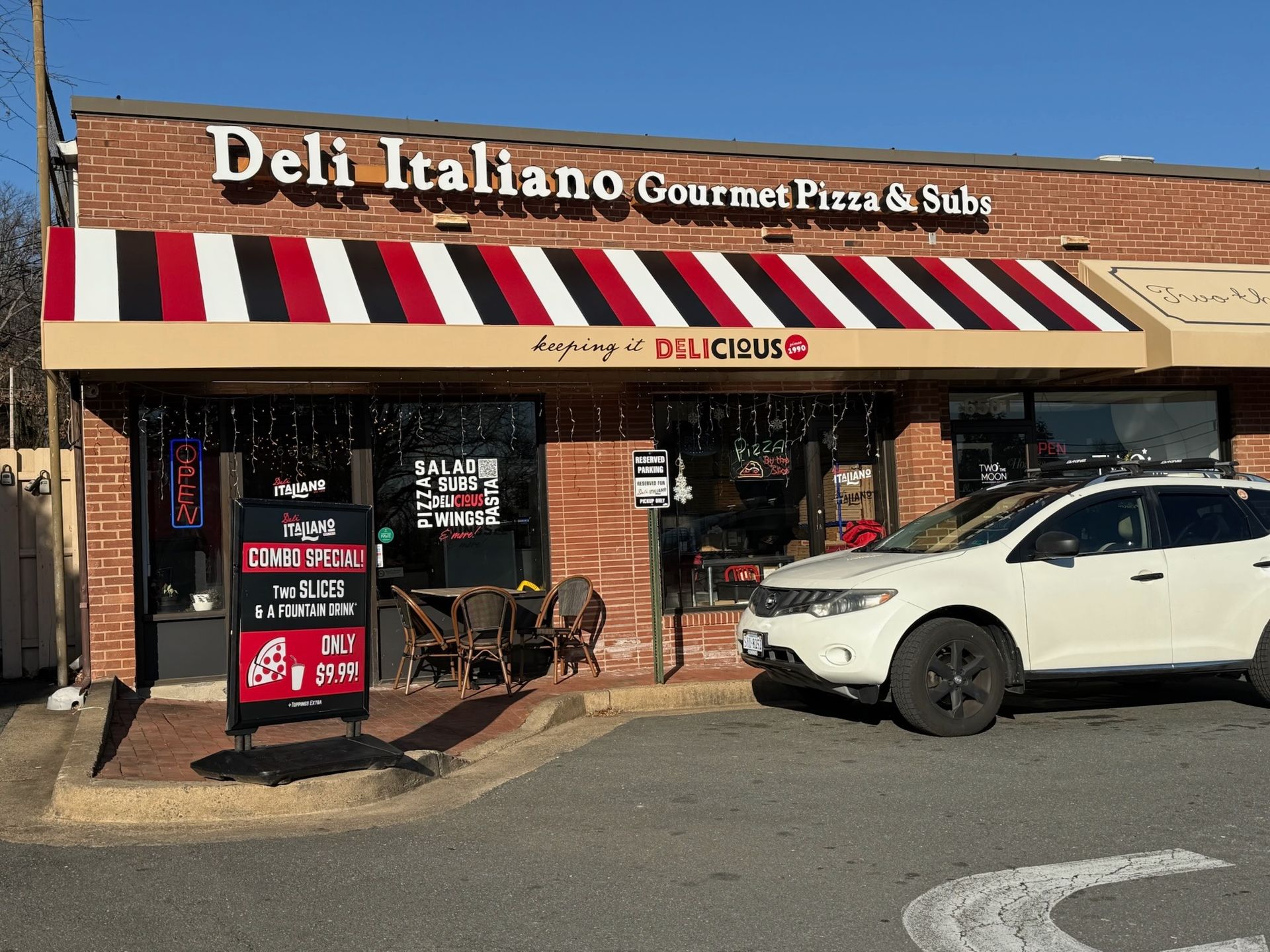 Deli Italiano storefront with red-and-white awning and a white SUV parked outside.