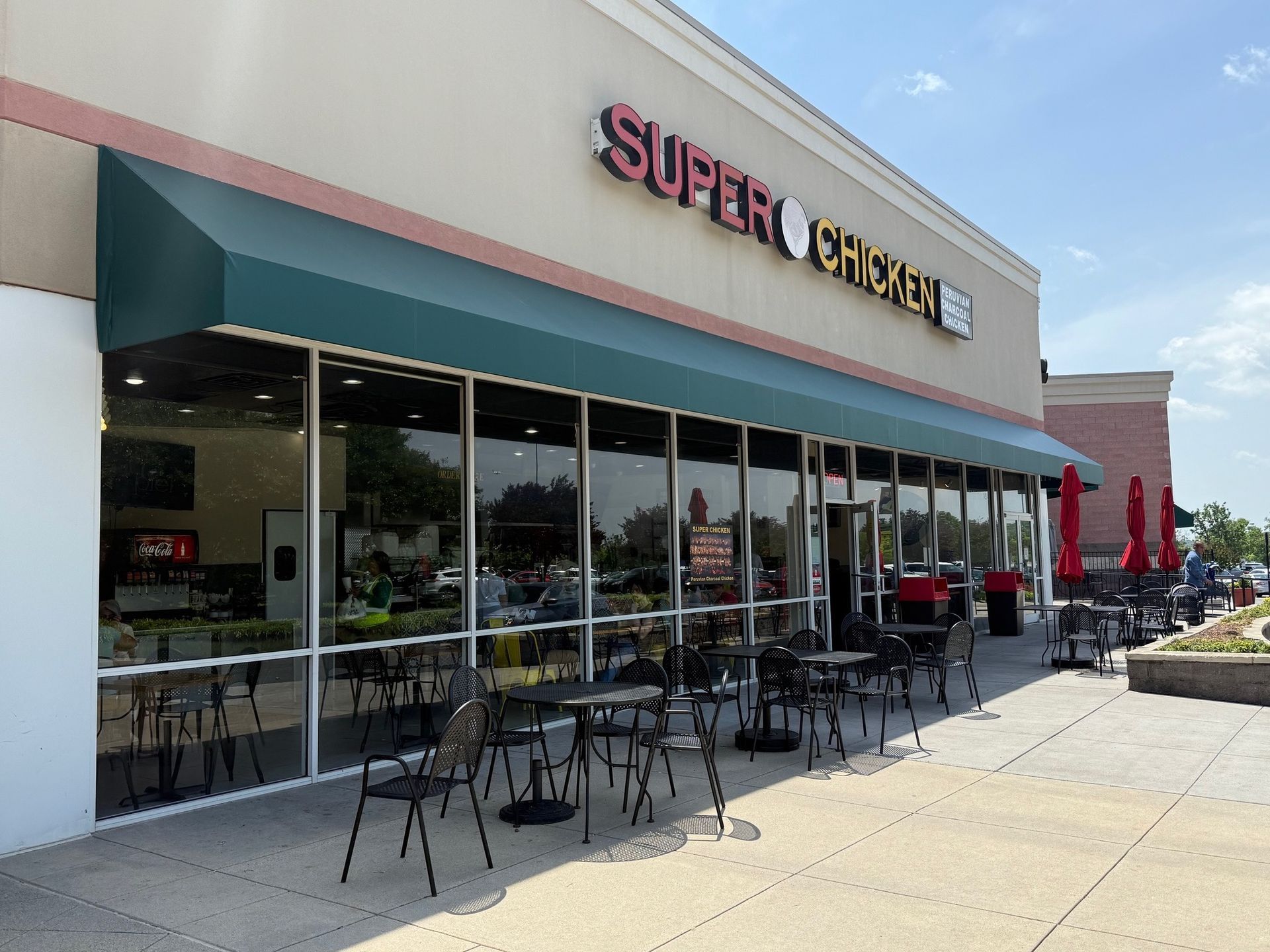 Super Gyros restaurant with outdoor patio seating and red umbrellas on a sunny day.