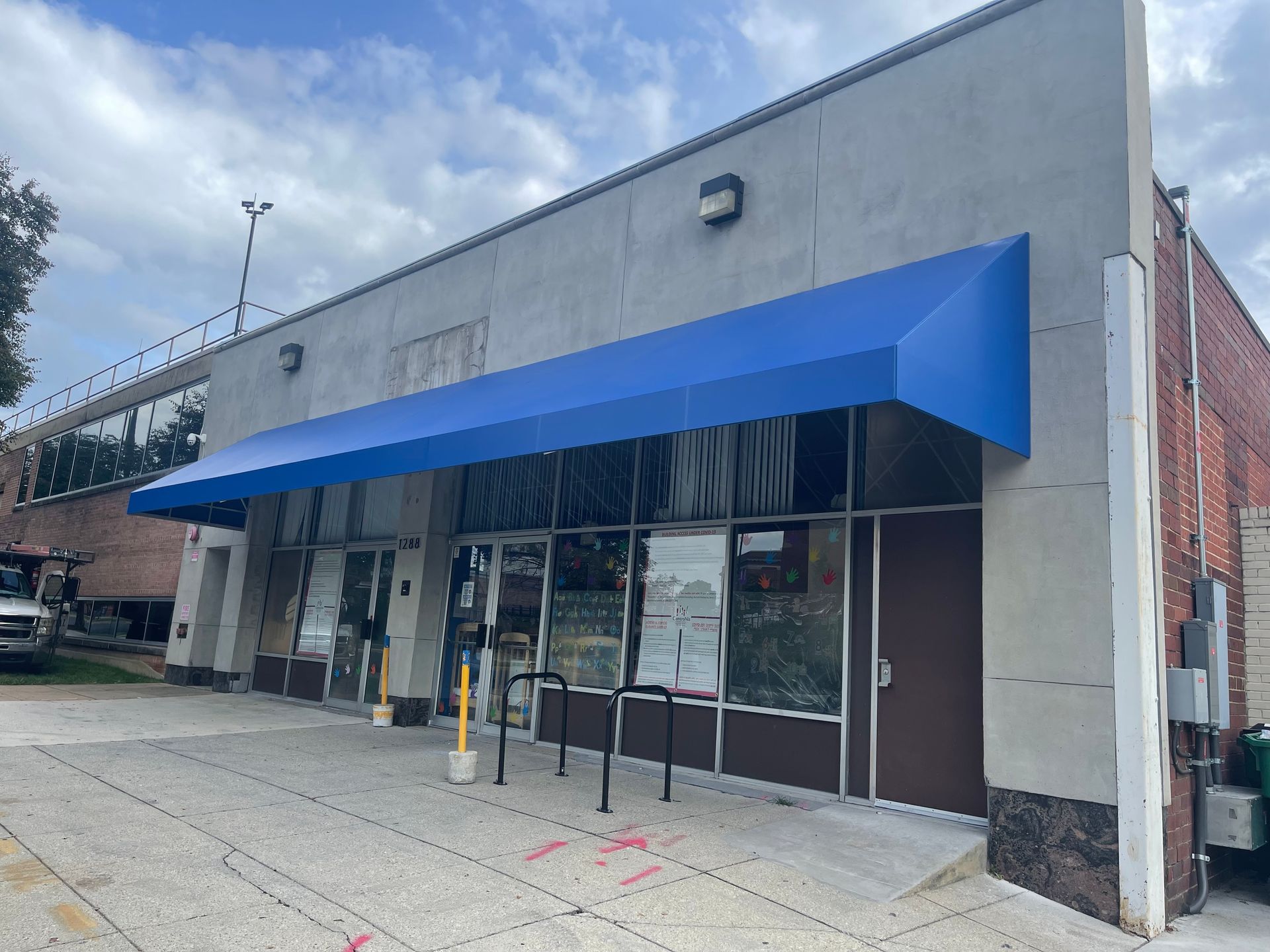 Storefront with bright blue awning and glass entrance on a city sidewalk.