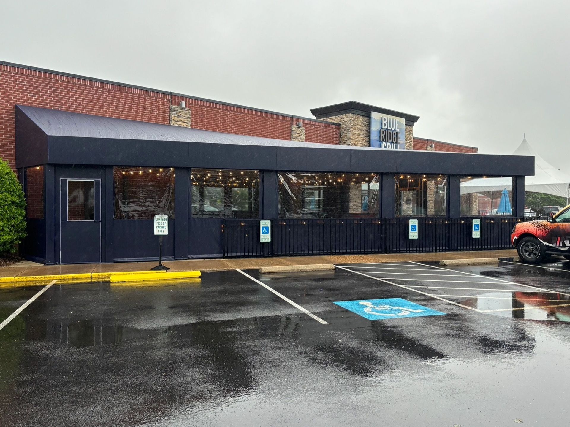 Rainy storefront with dark blue facade, empty parking lot, and a red ATV parked at the right.