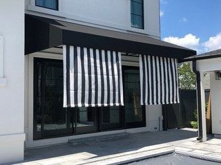 Modern storefront with black-and-white striped awnings and large glass windows on a sunny day