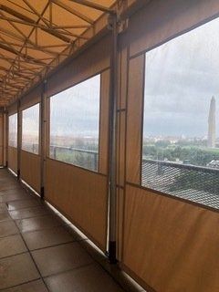 Covered walkway with wooden panels overlooking a city skyline and distant monument.