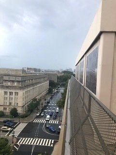 View from a building over a city street with zebra crossings, cars, and beige buildings under a cloudy sky