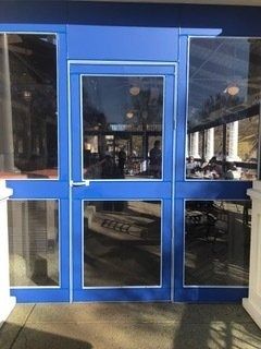 Blue glass double doors at a storefront entrance with windows on either side