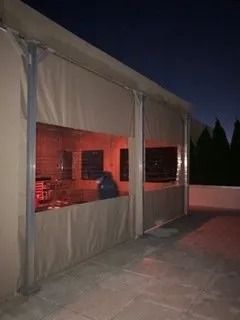 Nighttime outdoor tent with red-lit interior and a person seated inside near a wall opening