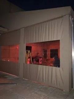 White tent-like structure with a large window opening, lit in red inside, on a concrete floor at night