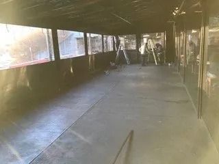 Empty indoor walkway with large windows and sunlight streaming in from the left